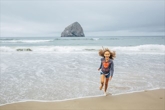 Mixed race girl running on beach