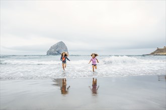 Mixed race sisters running on beach