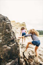 Mixed race sisters climbing on rocks