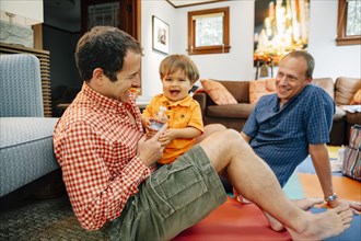 Gay fathers playing with baby son in living room
