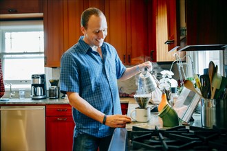 Caucasian man pouring coffee in kitchen