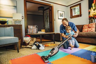 Father and son vacuuming living room