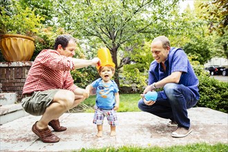 Gay fathers playing with baby son outdoors
