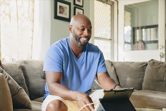 Black man using digital tablet in living room