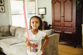 Mixed race girl holding light-saber in living room