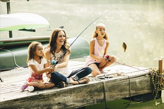 Mother and daughters fishing in lake