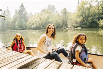Mother and daughters sitting in canoe in lake