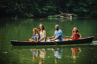Family sitting in canoe in lake