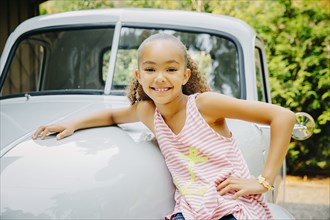 Mixed race girl leaning on car