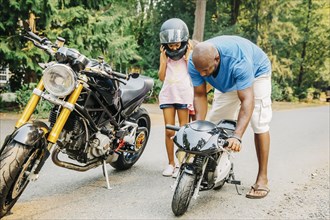 Father helping daughter with miniature motorcycle
