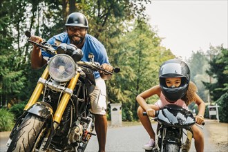 Father and daughter sitting on motorcycles