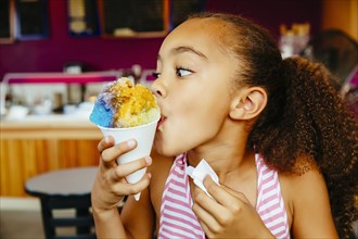 Mixed race girl eating snow cone