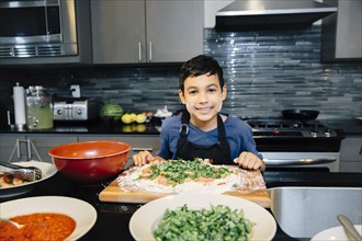 Mixed race boy cooking in kitchen
