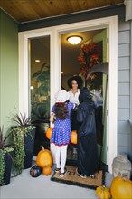 Woman receiving trick-or-treaters on Halloween