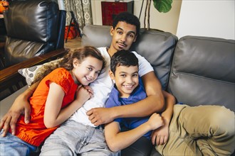 Mixed race brothers and sister laying on sofa