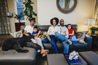 Family watching television on sofa