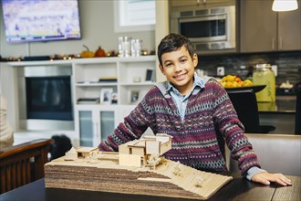 Mixed race boy smiling with model house