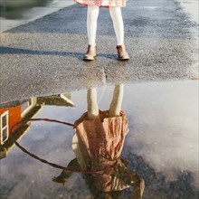 Mixed race girl and plastic hoop reflected in puddle
