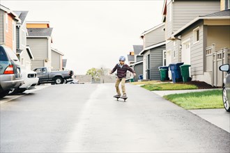 Mixed race boy riding skateboard on street