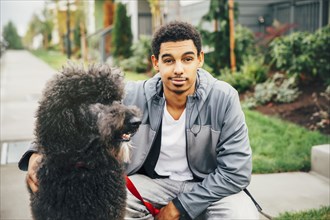 Mixed race man petting dog on sidewalk