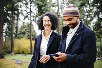 Couple using cell phone in park