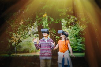 Mixed race children using virtual reality goggles outdoors