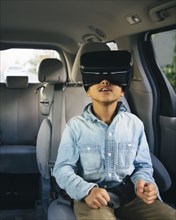 Mixed race boy using virtual reality goggles in car