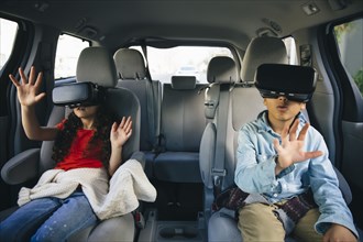 Mixed race children using virtual reality goggles in car