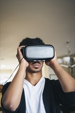 Mixed race man using virtual reality goggles