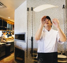 Chef tossing pizza dough in restaurant in kitchen