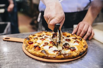 Chef slicing pizza in restaurant kitchen