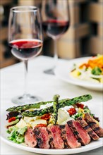 Plate of grilled meat and asparagus salad with wine