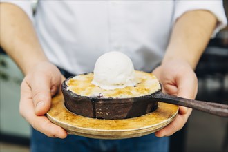 Caucasian waiter holding skillet dessert