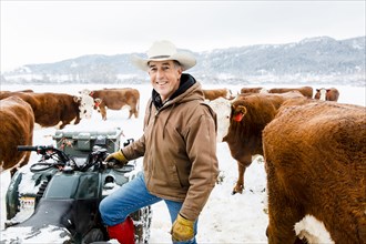 Caucasian farmer with cattle in snowy field
