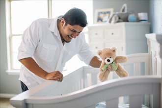 Hispanic father waving toy for baby in nursery