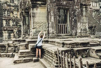 Caucasian tourist photographing Angkor Wat ruins