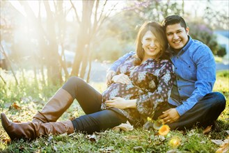 Pregnant Hispanic couple smiling outdoors