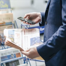 Caucasian businessman using cell phone at newspaper stand