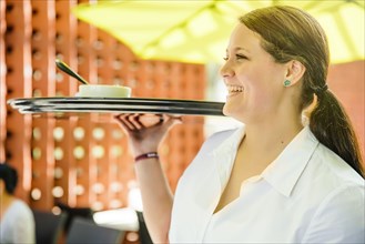 Caucasian waitress carrying tray in restaurant