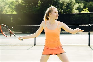 Caucasian woman swinging tennis racket on tennis court