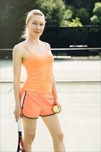 Smiling Caucasian woman posing on tennis court