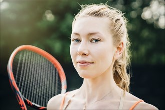 Smiling Caucasian woman holding tennis racket
