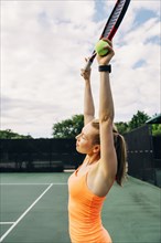Caucasian woman stretching arms on tennis court