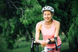 Smiling Caucasian woman leaning on bicycle handlebar