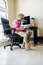 Black woman playing with dog in home office