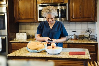 Black woman texting on cell phone in domestic kitchen