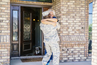 Black soldier hugging wife in doorway
