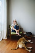 Caucasian woman sitting in armchair near dog
