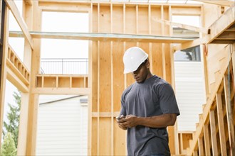 Black construction worker texting on cell phone