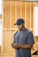 Black man texting on cell phone at construction site
